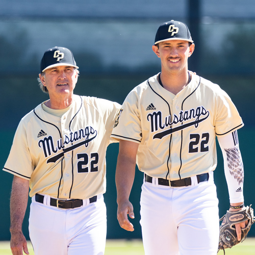 Coach Larry Lee and Brooks Lee wearing Cal Poly uniforms walk on a baseball field