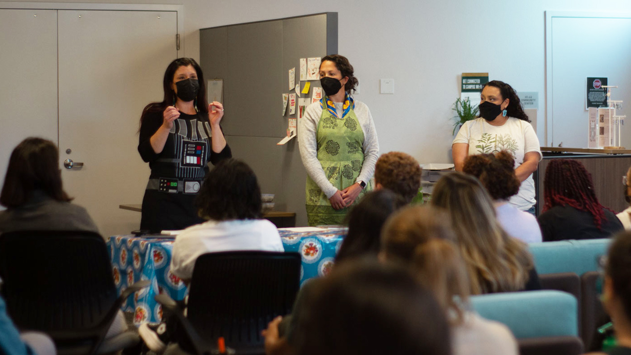 Professors Jenell Navarro and Lydia Heberling and Cheryl Flores host a presentation for an audience while wearing masks