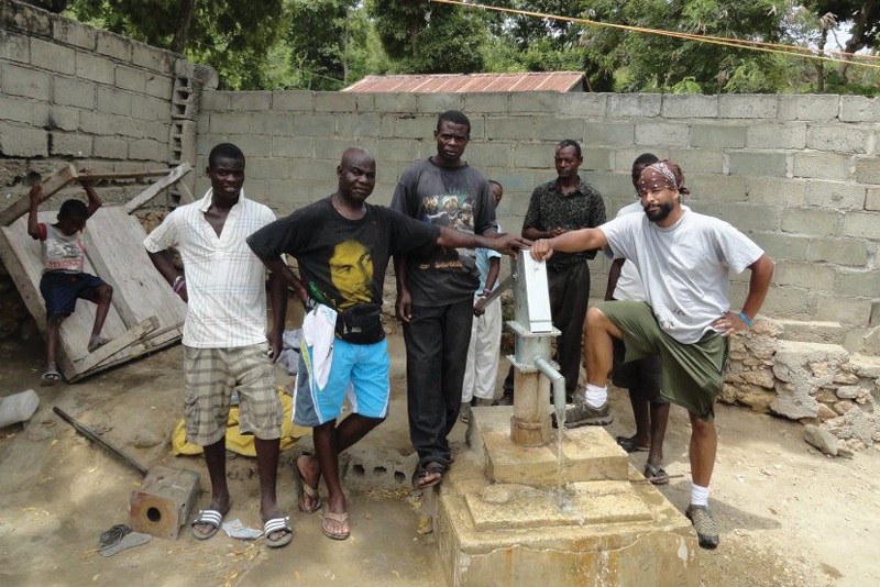 Six people stand around a newly retrofitted well in Haiti