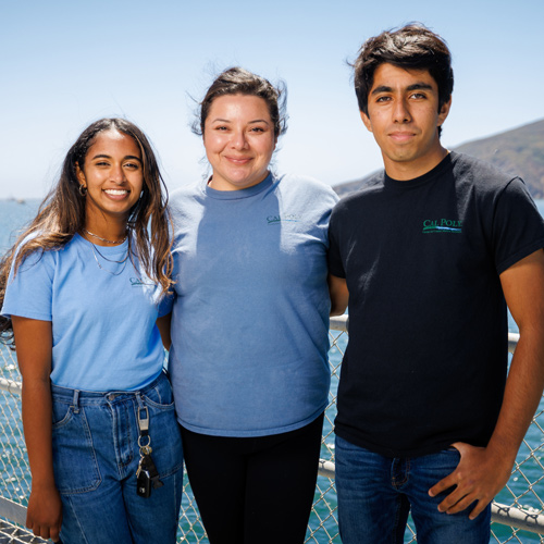Three student ambassadors smile on a sunny day on the Cal Poly Pier