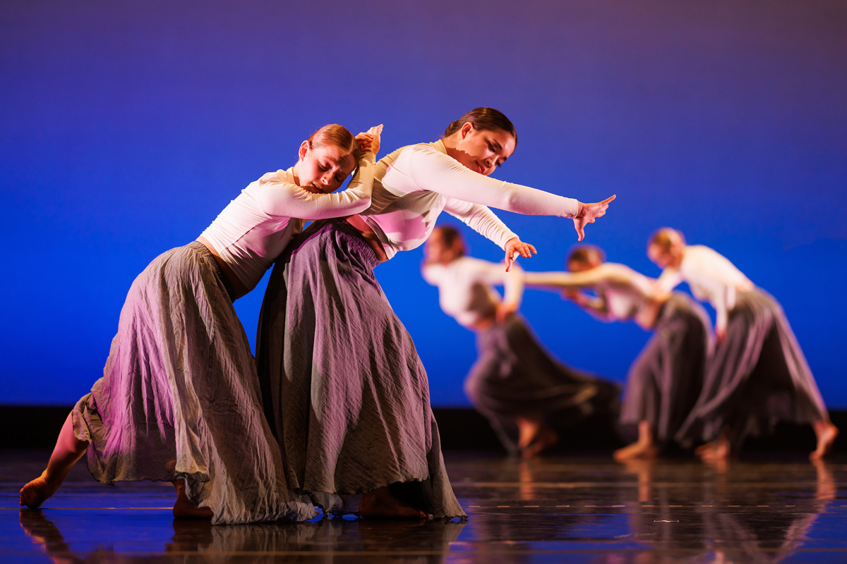 Dancers in flowing skirts take graceful postures on stage