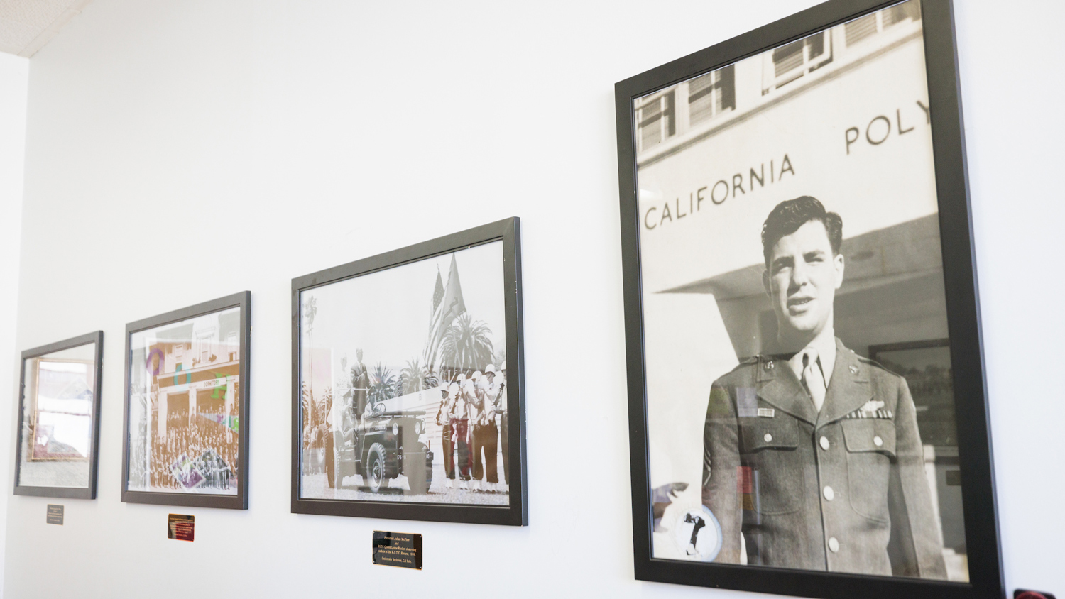 Four framed black-and-white photos of military veterans and military parades hung on a wall. 