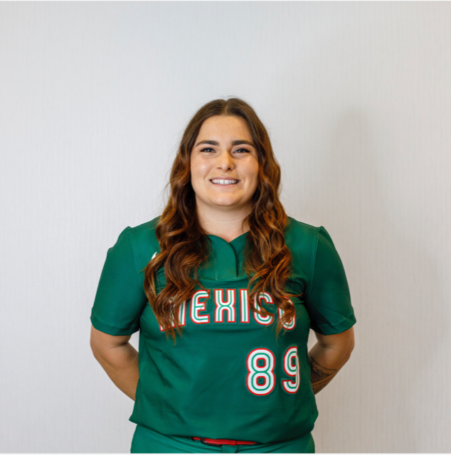 Softball player Sierra Hyland poses with her hands behind her back, looking straight at the camera. She is wearing her Team Mexico uniform, which is green and says Mexico across the front and the number 89.