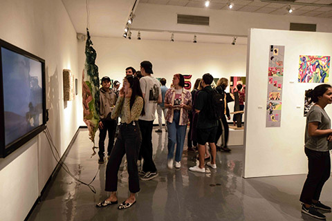 People look at exhibits in the University Art Gallery