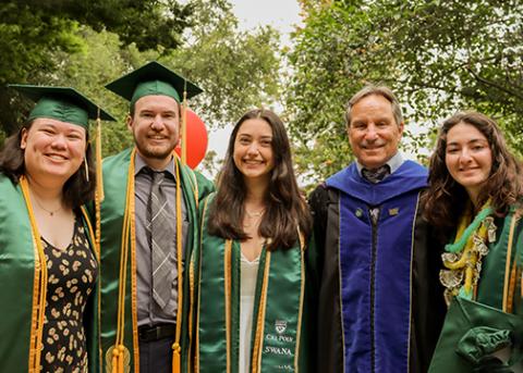Dean Thulin pictured with four students all wearing commencement regalia