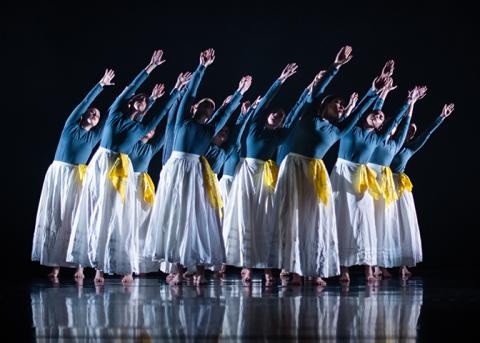 Orchesis Dance Company dancers wearing the same blue white and yellow costume motion with their arms