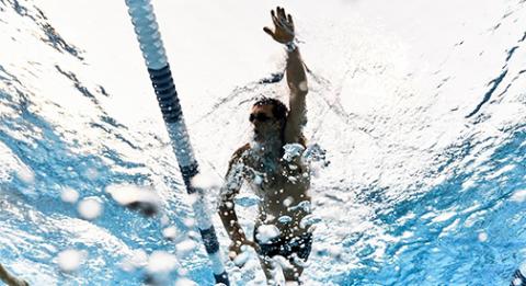 An underwater photo looking up at a lap swimmer in a pool