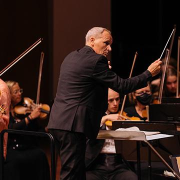 A conductor with symphony violinists in front of him