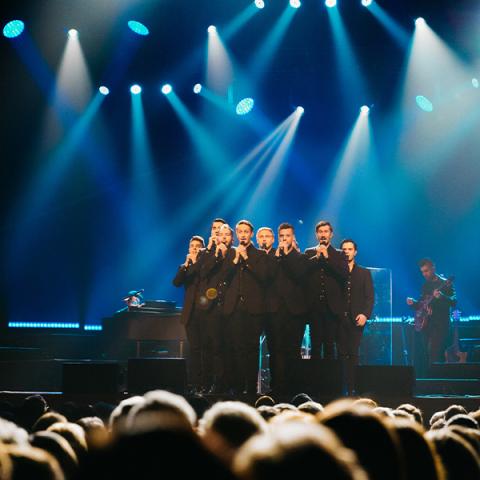 Bright blue stage lights shine up the ten TENORS performing  in the center