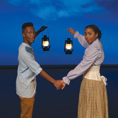 two people hold lanterns against a dark blue sky