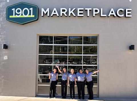 UU Plaza entrance to 1901 Marketplace w five workers standing in front of closed glass roll-down door