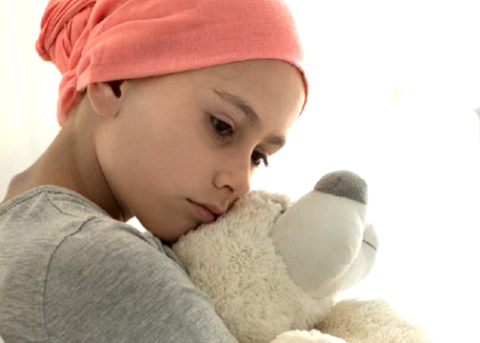 Young girl with scarf covering the top of her head hugs a teddy bear