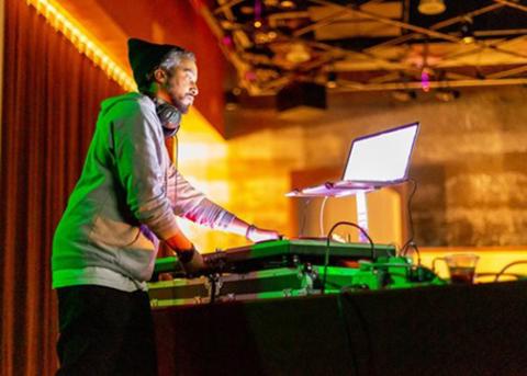 Shaolin Jazz DJ spins records under bright colored stage lights