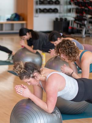 Students use an exercise ball during a fitness class