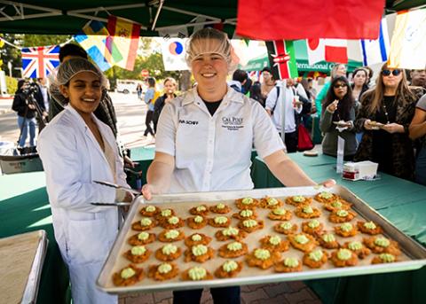 Student servers pose with a tray of treats at a past Taste of the World