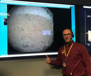 Standing near an image projected by NASA’s lander, named InSight, Cal Poly alumnus Tim Weise gives a thumbs up at mission control 15 minutes after InSight’s dramatic Mars touchdown.