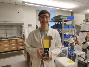 Student McClane Howland poses in a Cal Poly lab with compounds that will be tested as potential COVID-19 treatments.