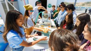 Cal Poly students show high school students sea animals in touch tanks during a tour of the Cal Poly Pier