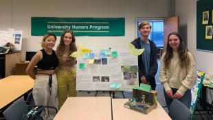 A group of honors program students poses with their project, Serenity Garden, which involves both a posterboard and a diorama.