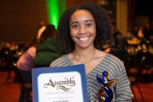 Genesis Glover holds a certificate of recognition and a glass award