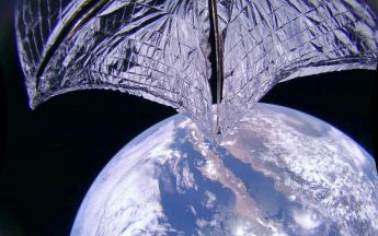 A silver fabric sail stretches across the top of a point-of-view image of the Earth from space