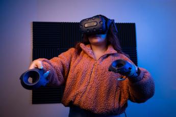 Cal Poly computer science major Zahnae Aquino uses an HTC VIVE headset and controllers to navigate a virtual reality environment that she created with fellow student Josie Grundler.