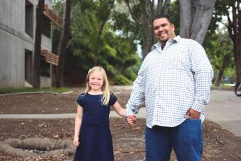 Cal Poly student Jeremiah Hernandez smiles while holding hands with his daughter, Savannah
