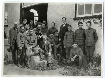 A group of men sit in front of a building on Cal Poly's campus in about 1918.