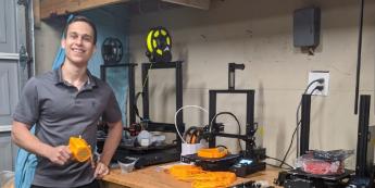 Engineering student Cristian Sion poses with a respirator and 3D printers in his garage.