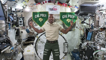 Alumnus Victor Glover floats center screen, speaking into the camera aboard the International Space Station
