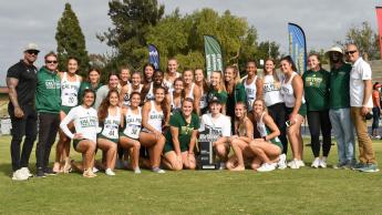 The Cal Poly Women's Track and Field team celebrates on the field around a "conference champions" trophy.