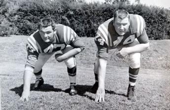 A black and white photograph of two men in football uniforms in the 1950s.