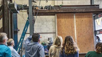 Cal Poly students, faculty, donors and guests observe a shear wall test in the CAED High Bay Laboratory.