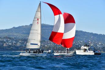 The Cal Poly Sailing Club's sailboat, featuring a giant red-and-white-spinnaker sail, racing in the ocean during the Los Angeles Harbor Cup.