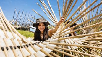 A student wearing a hat installs a bamboo structure in Poly Canyon during Design Village