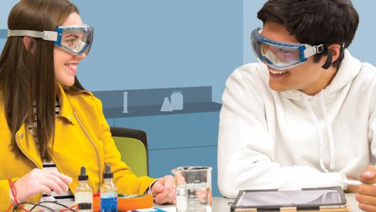 Two students look at each other with protective glasses on