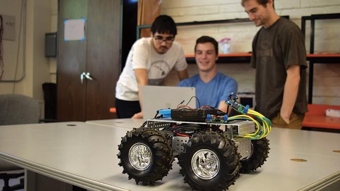 Computer Engineering students with model autonomous navigating battery-powered car