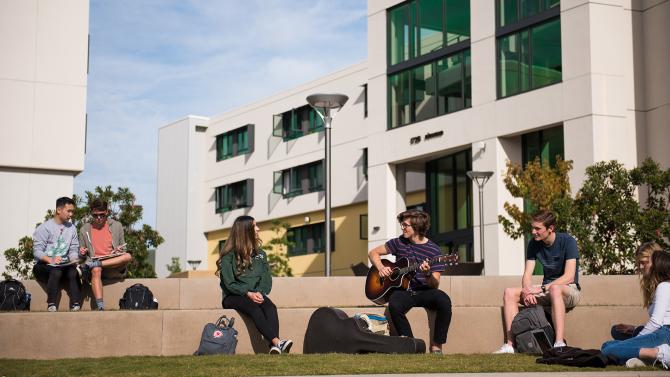 Students in front of Yakitutu dorms listening to guitar