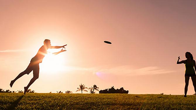 Two Cal Poly students play frisbee as the sun sets