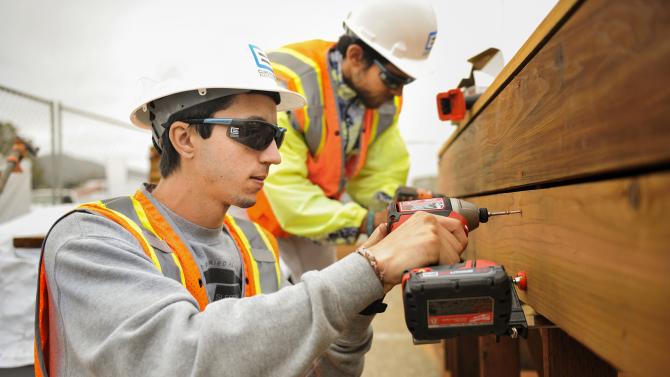 Student using nail gun to build a structure during the Solar Decathlon