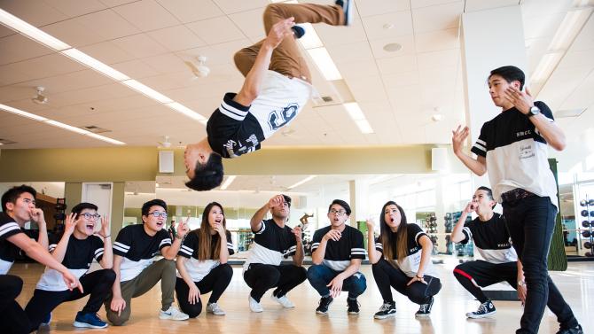 Student doing a back flip with a group standing around him.
