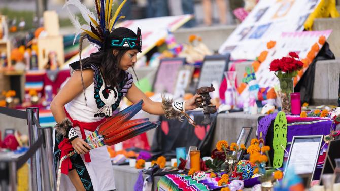 Woman places items on a shrine during dia de los muertos
