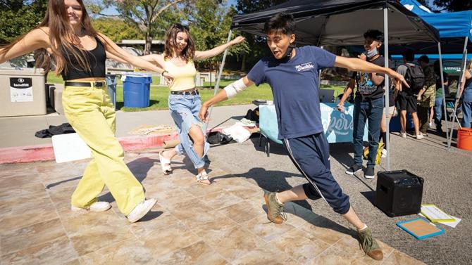 Three students dancing on campus