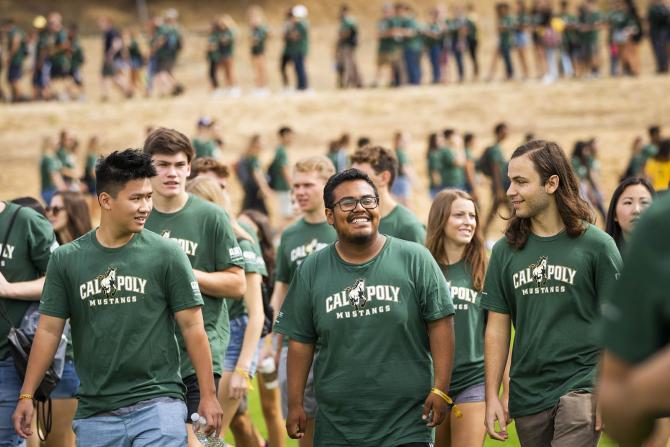 Three students walk in a group at a large campus event.