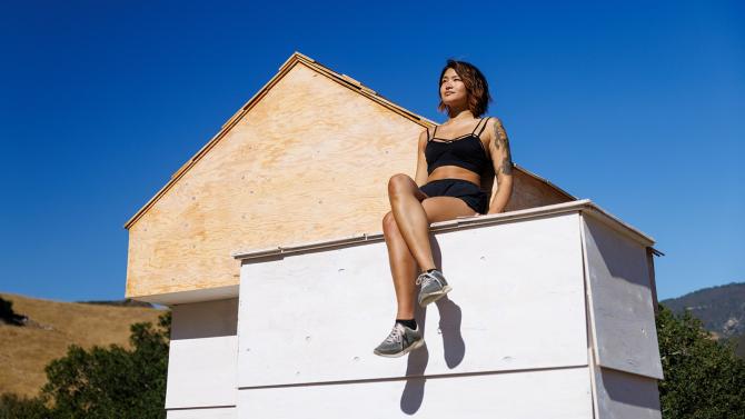 Student Dara Lin sits atop her structure built in Poly Canyon