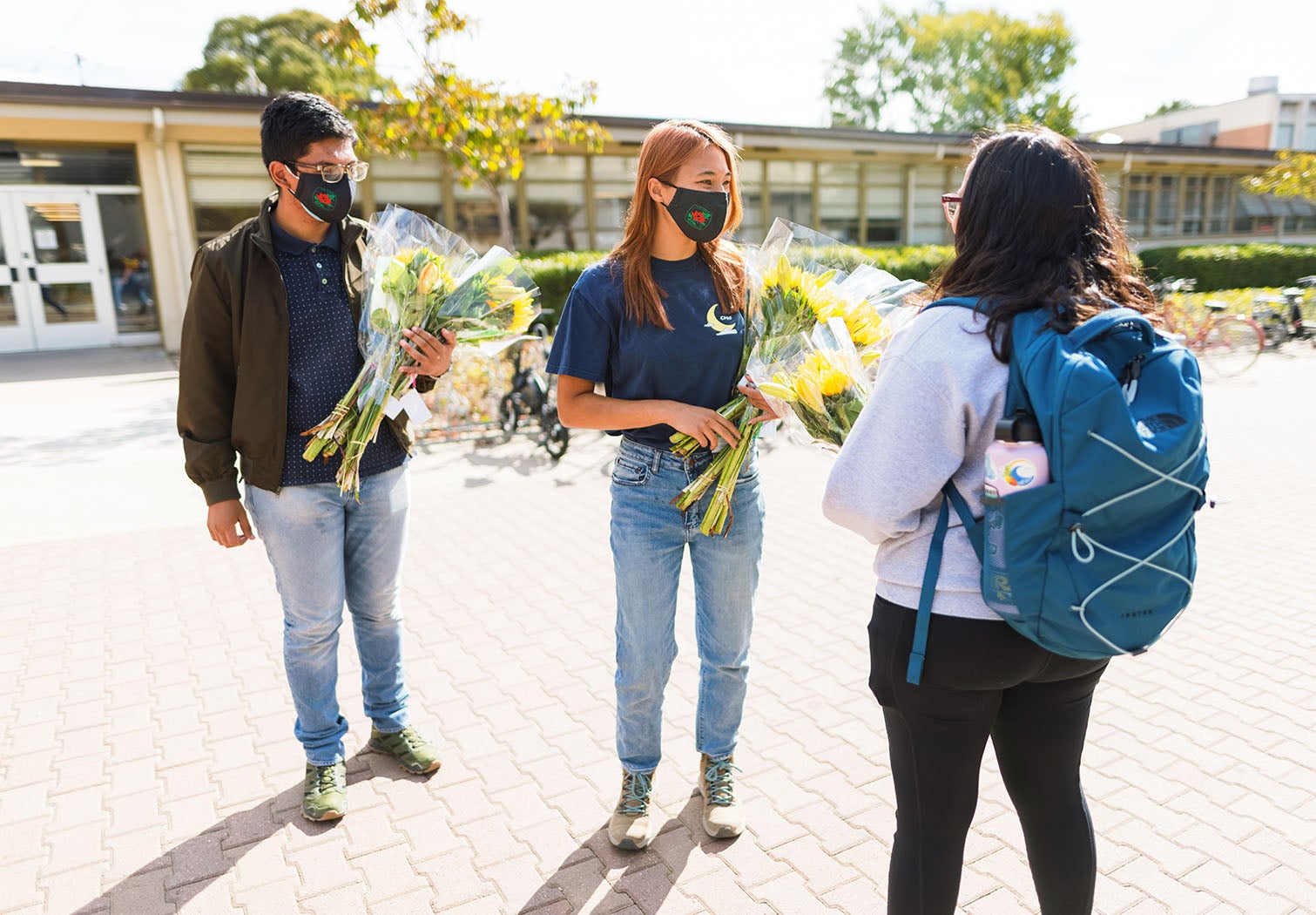 Students Jesus Velasquez and Samantha Gustafson surprise a campus community member with flowers.