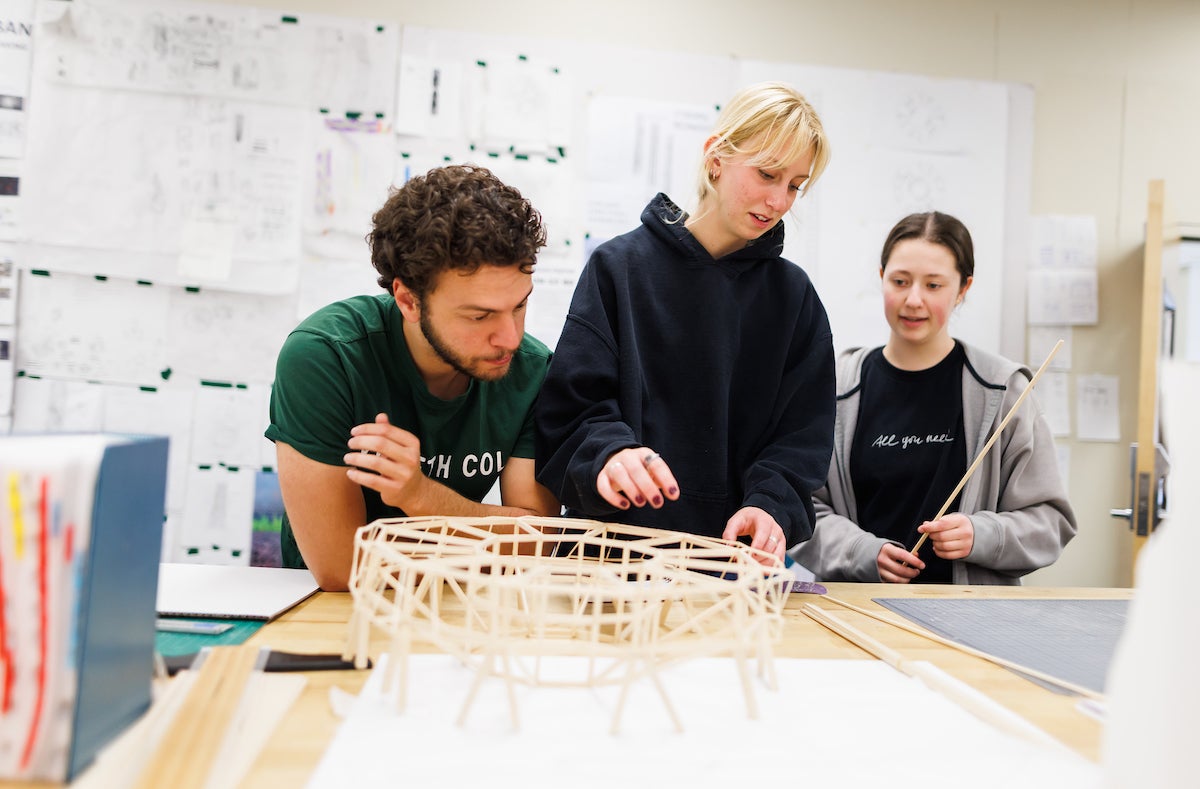 Architecture students put together a wooden scale model of a skyscraper.