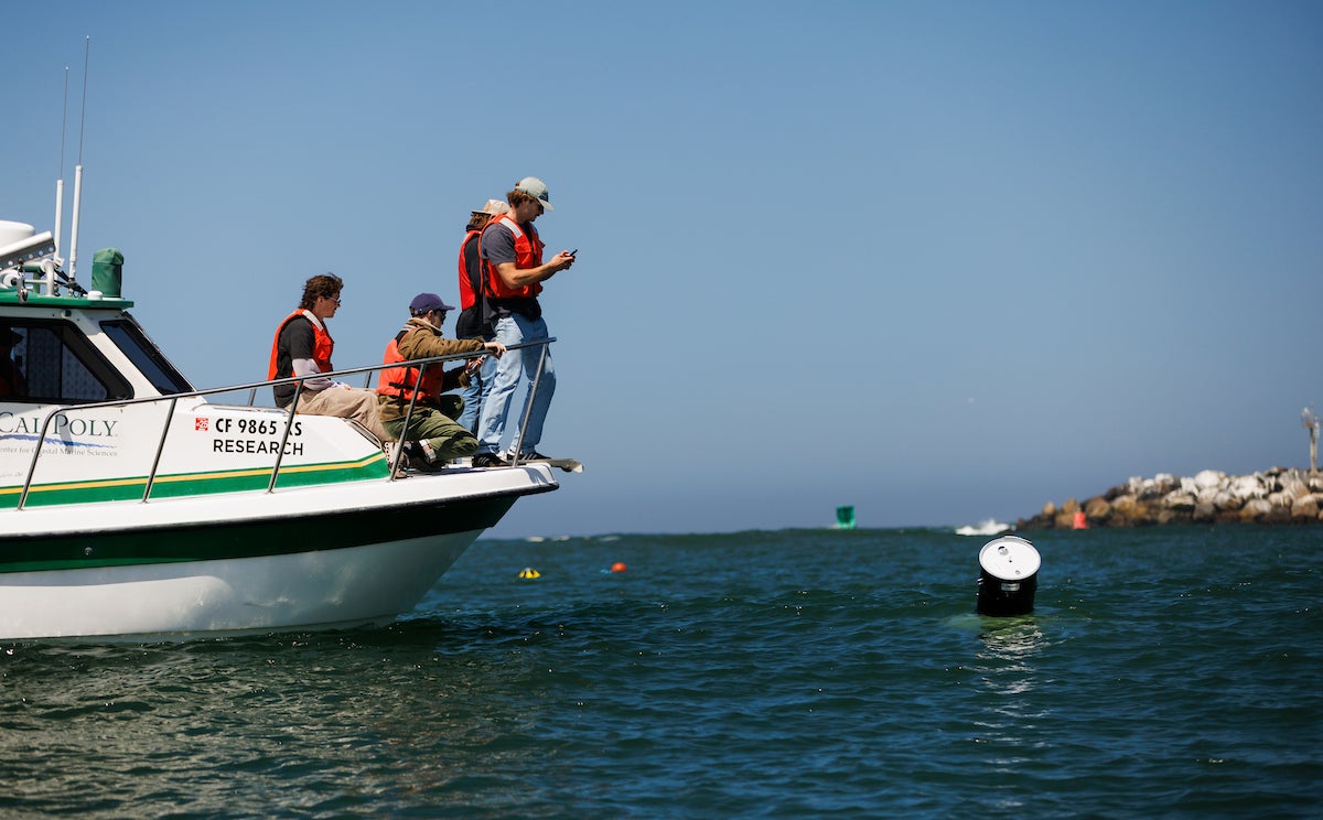 Students stand on a research vessel to test their ocean powered generator in Morro Bay.