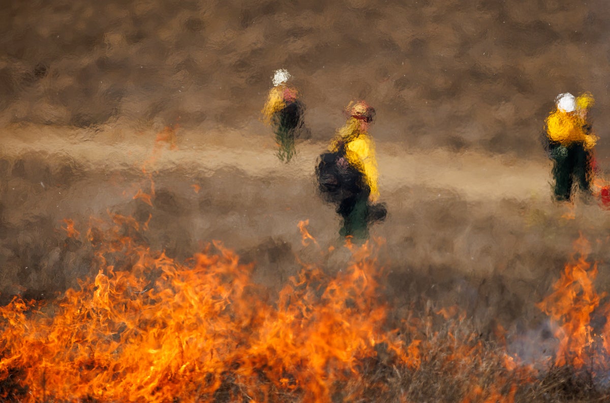 Fire in the foreground creates a hazy view of students in the background.