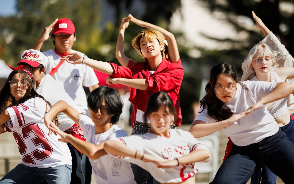 A group of students in red and white clothes strikes a pose during a dance performance.